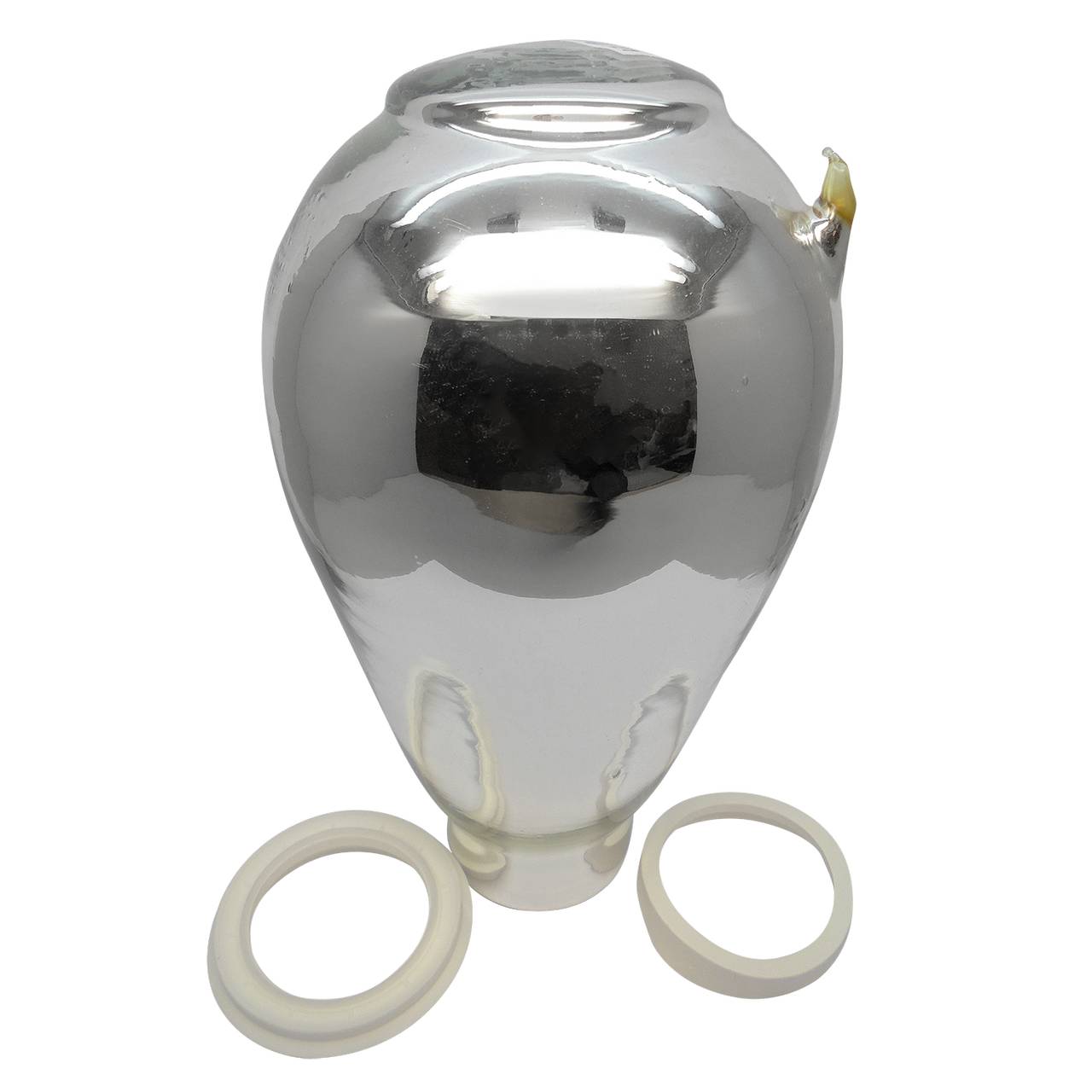 Auf dem Bild ist eine glänzende, silberfarbene Vase mit einer bauchigen Form zu sehen. Vor der Vase liegen zwei weiße, ringförmige Objekte. Die Oberfläche der Vase reflektiert das Licht stark.