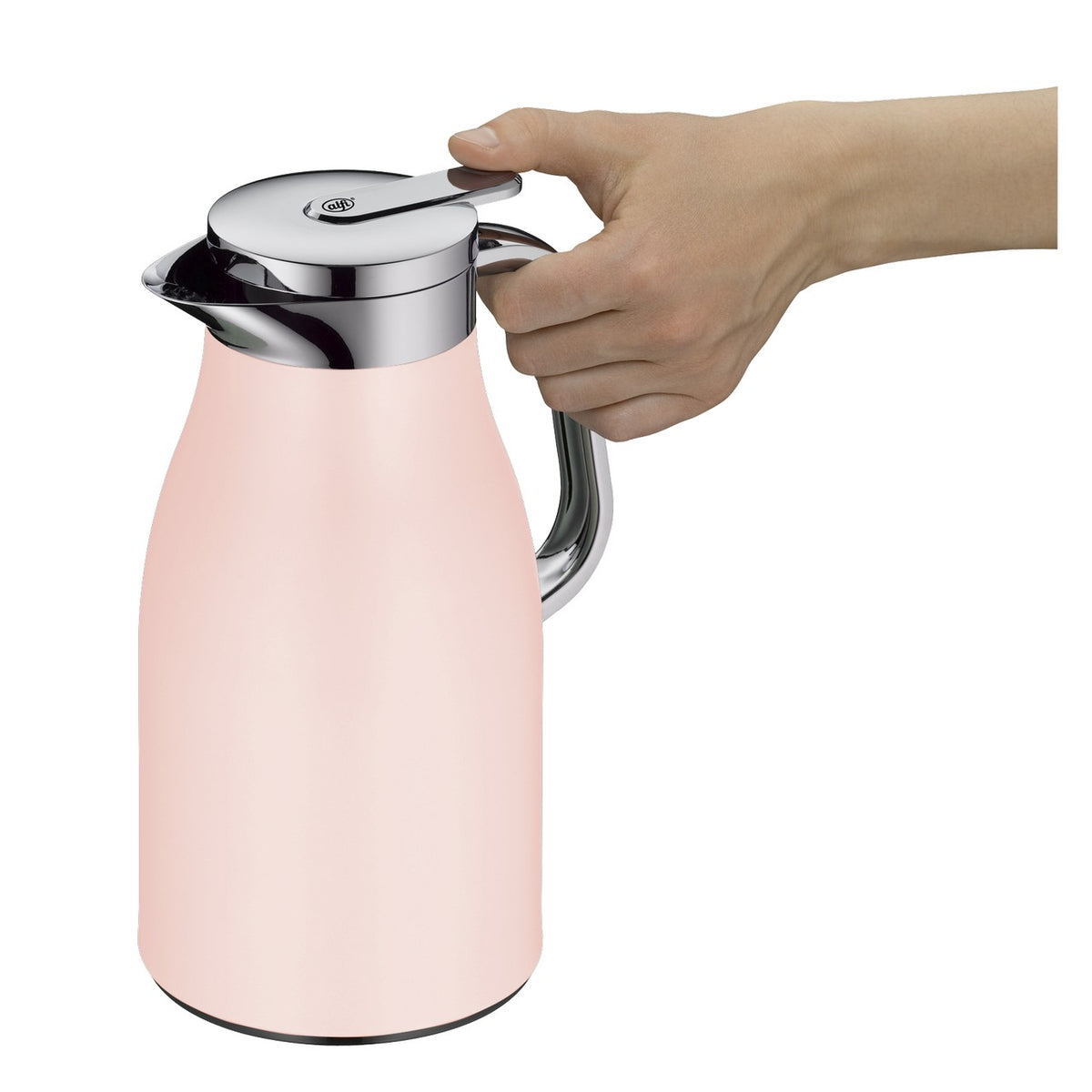 Auf dem Bild steht eine rosa Thermoskanne mit einem metallischen Griff auf einer Holzarbeitsplatte. Daneben liegt ein graues Tuch, und ein Teller mit Croissants steht darauf. Im Hintergrund sieht man ein Fenster, grüne Pflanzen und Küchenutensilien.