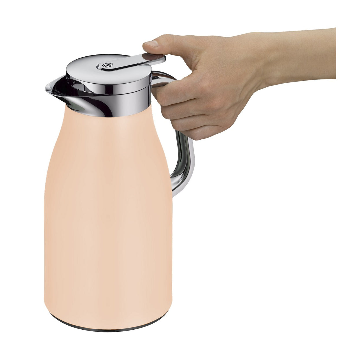 Im Vordergrund steht eine elegante, rosafarbene Thermoskanne mit glänzendem Metallgriff auf einem gestreiften Tuch. Unscharf sind Küchenutensilien in einem Behälter und ein Sitzbereich erkennbar. Die Szene wirkt modern und stilvoll.
