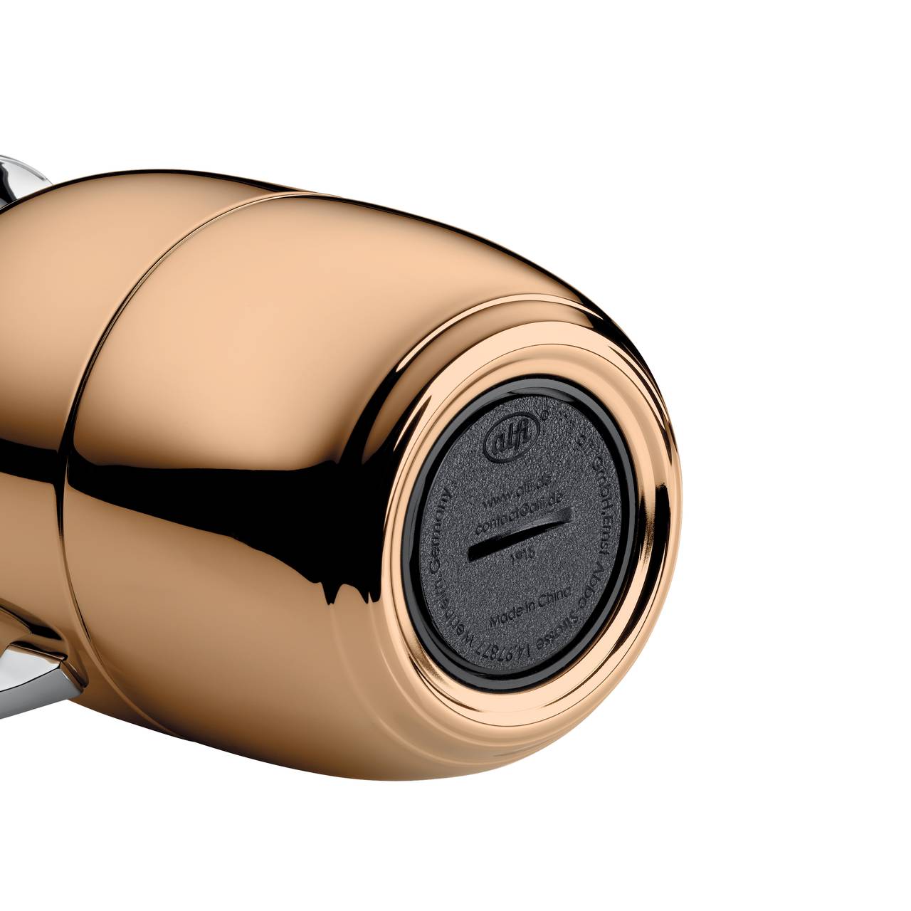 Das Bild zeigt den unteren Teil eines glänzenden, goldfarbenen, zylindrischen Objekts, möglicherweise ein Küchengerät. Auf der Unterseite befinden sich Prägungen und eine Öffnung mit schwarzem Einsatz.