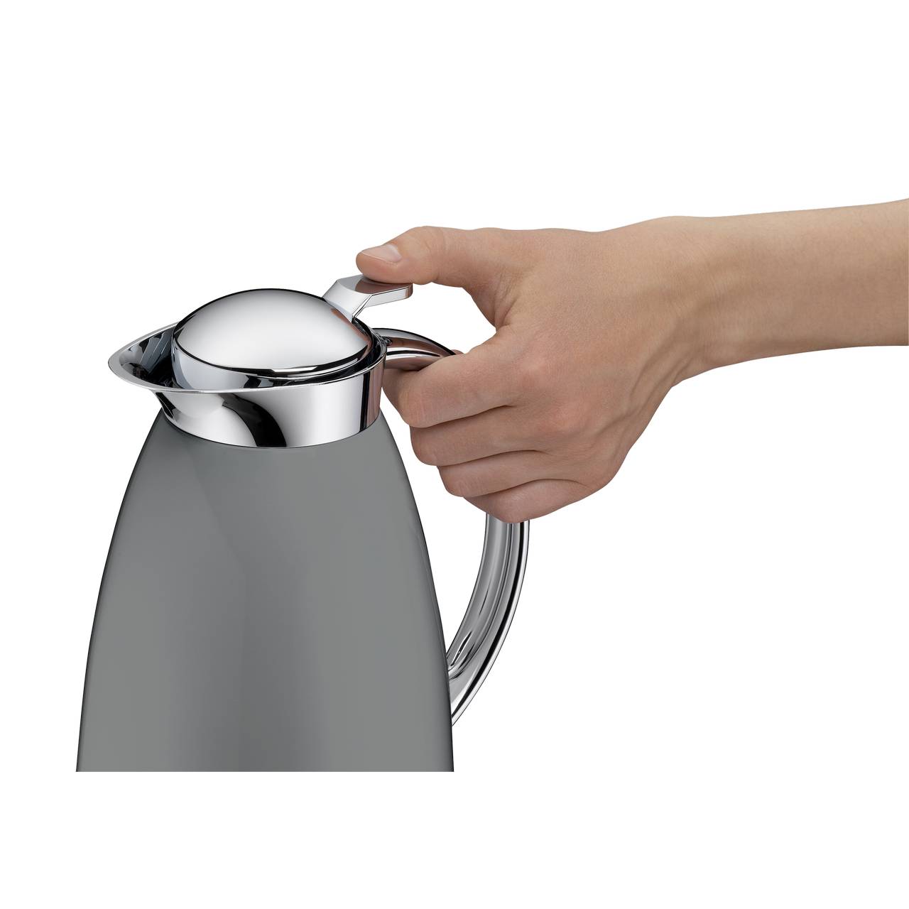 Eine Hand greift den Deckel eines silbernen Wasserkochers. Der Wasserkocher hat einen gebogenen Griff und eine glatte, glänzende Oberfläche.