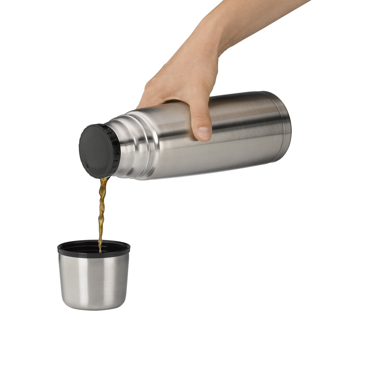 Eine Hand hält eine Edelstahl-Thermoskanne und gießt eine Flüssigkeit in einen passenden Becher darunter. Der Hintergrund ist neutral und hebt die silbernen Objekte hervor.