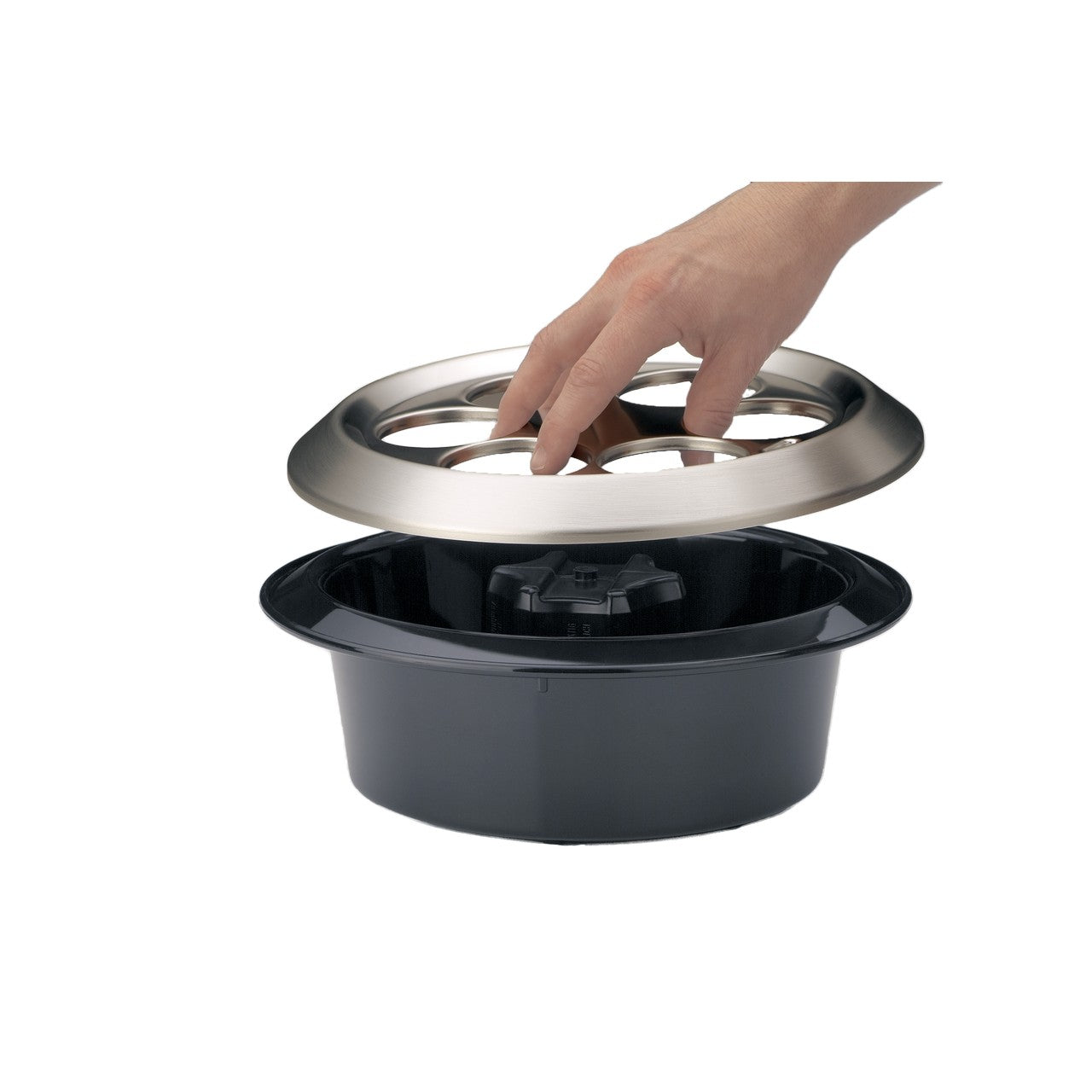Ein schwarzer Topf mit einem abnehmbaren, glänzenden Deckel wird von einer Hand gehalten. Die Hand hebt den Deckel leicht an, sodass man den weißen Inhalt im Topf sehen kann. Der Hintergrund ist einfarbig und schlicht.