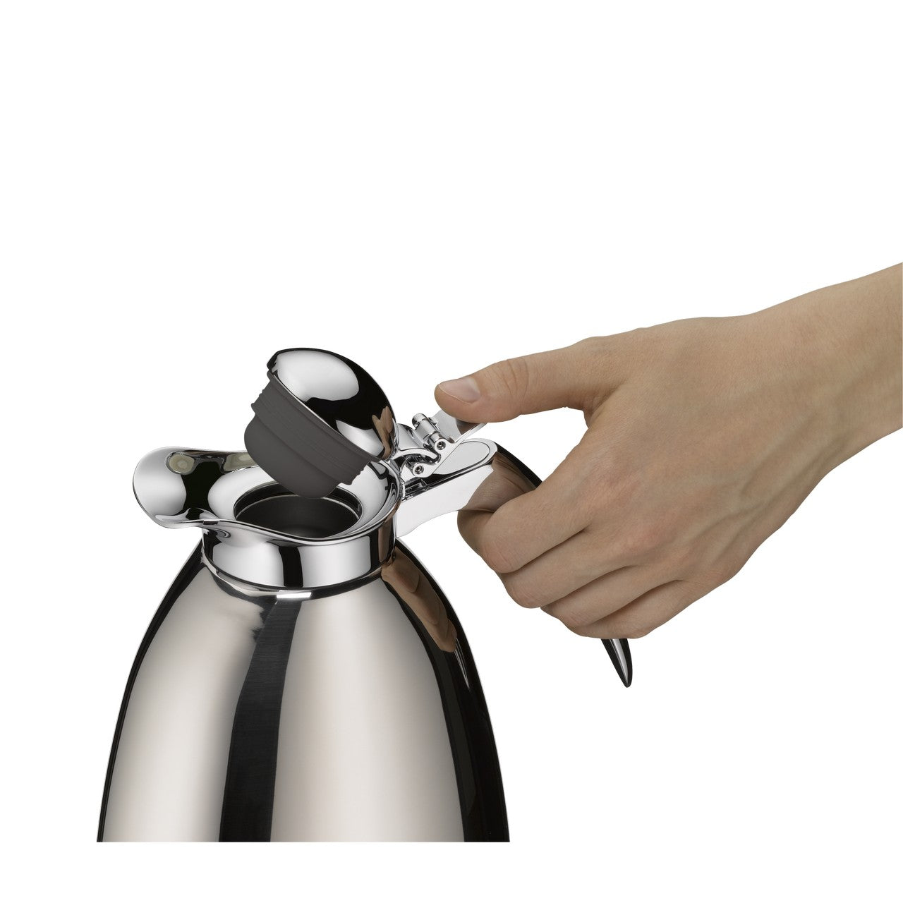 Eine Hand hält den Griff einer glänzenden, metallischen Thermoskanne, deren Deckel geöffnet ist. Der Deckel hat einen Klappmechanismus, der durch einen Daumendruck auf einen Hebel bedient wird.