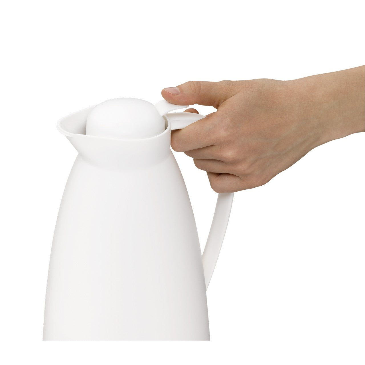 Eine Hand hält eine weiße Thermoskanne am Griff. Die Kanne hat einen abgerundeten Deckel und steht aufrecht.