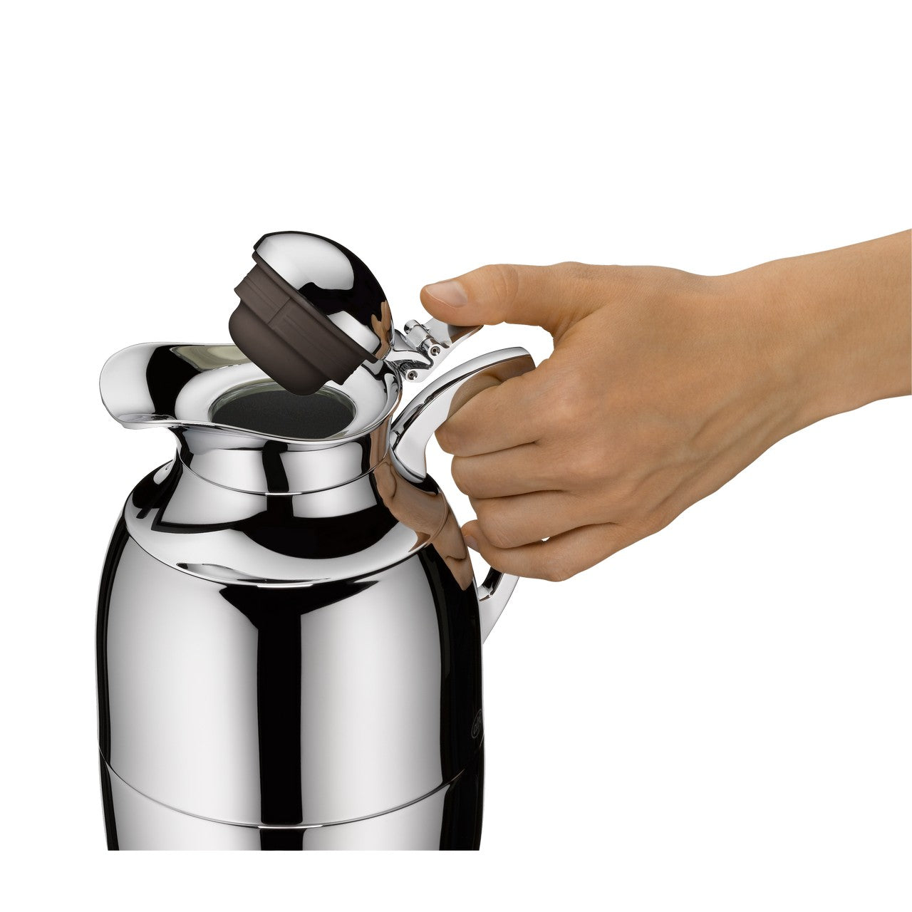 Eine Hand öffnet den Deckel einer glänzenden, silbernen Isolierkanne. Die Kanne hat ein geschwungenes Design und reflektiert das Licht. Der Deckel ist zur Seite gekippt und über dem offenen Ausguss zu sehen.